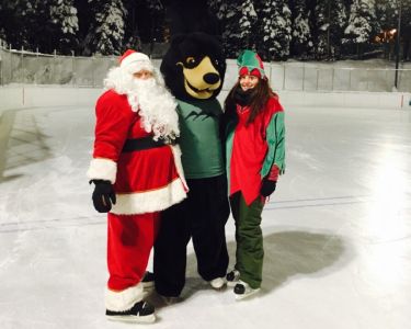 Santa, bear and skater posing for photo on the ice